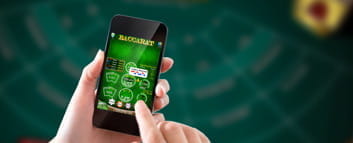 Ein Smartphone wird gehalten, auf dem Baccarat Online gespielt wird.