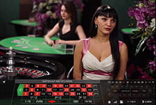 Auf diesem Bild sieht man einen weiblichen Live Dealer vor einem Roulettekessel.
