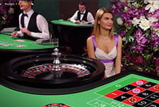 Live Croupiers warten an ihren Spieltische auf Gäste.