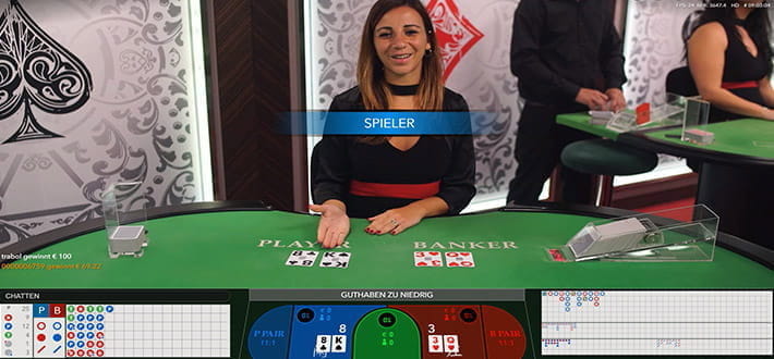 Live Baccarat in der Punto Banco Variante, bereitgestellt von Evolution Gaming für das Betchan Live Casino. Der Dealer am Spieltisch bedeutet mit seiner rechten Hand, dass in dieser Runde die Wette auf den Gewinn der Spieler siegbringend war.