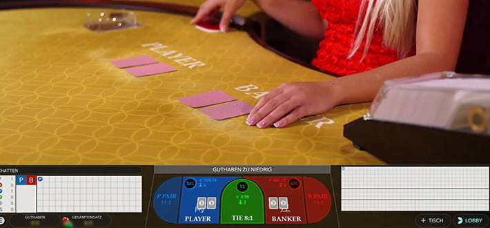 Ein Live Baccarat Squeeze Spieltisch von Evolution Gaming im Live Bereich vom Betchan Casino. Im Bild sind groß die gepflegten Hände des Dealers zu sehen, der gleich die Karten gemäß des Squeeze Rituals aufdecken wird.