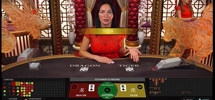 Live Baccarat in der Variante Dragon Tiger im JellyBean Live Casino. Die beiden Spielkarten sind gezogen, in diesem Spiel gewinnen alle, die auf Tiger gesetzt haben. Die Tiger Karte ist Pik König, während der Drache nur auf Pik 8 kommt. Der Dealer am Tisch erklärt offiziell die Gewinnerkarte.
