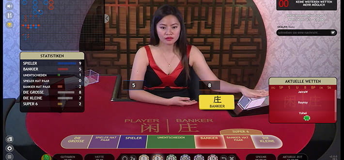 Live Super 6 Baccarat von Extreme Live Gaming im Live Casino von JellyBean Casino. Der Dealer sitzt hinter dem Spieltisch, der mit asiatische Symbolen verziert ist. Links im Bild sind weitere Informationen und Spielstatistiken eingeblendet.