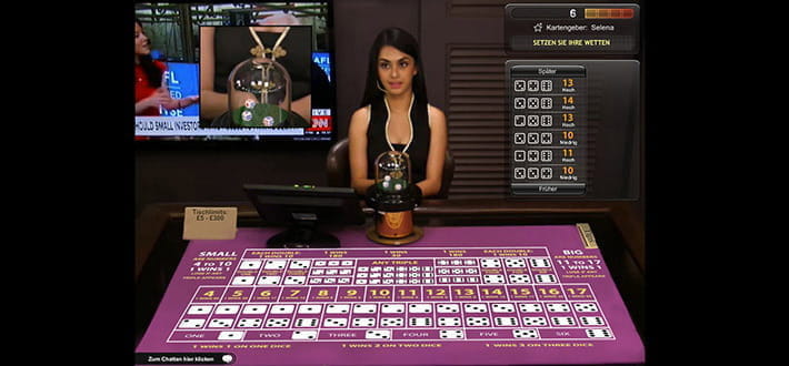 Ein Live Sic Bo Spieltisch von Playtech im Ladbrokes Live Casino. Der Tisch mit dem typischen Setztableau nimmt den größten Teil des Bildes ein. Der Dealer sitzt am Tisch, unmittelbar vor ihm befindet sich der Glaszylinder mit den Würfeln.Links oben wir in einem kleinen Fenster das Werfen der Würfel in Großaufnahme gezeigt. Rechts im Bild sind Spielstatistiken abrufbar.