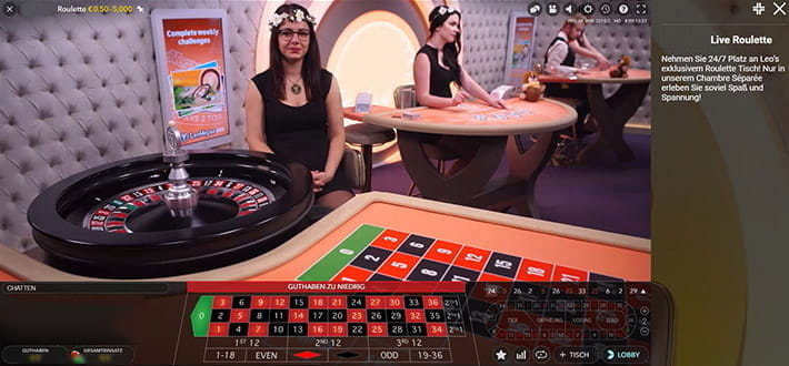 Das Bild zeigt einen privaten LeoVegas Live Roulette Spieltisch. Der Dealer sitzt links hinter dem Roulettekessel und wartet, bis die Kugel in eines der Fächer fällt. Im Bildhintergrund sind weitere private Spieltische zu erkennen.