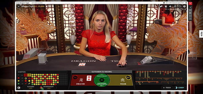 Der Live Dragon Tiger Spieltisch des Herstellers Evolution Gaming im Live Bereich von Royal Panda. Der Kartenwert für Drachen beträgt Karo Dame, der Dealer ist gerade im Begriff, die Tiger Karte aufzudecken. Der Spieltisch befindet sich in einem asiatisch angehauchten Ambiente.