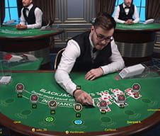 Zu sehen ist ein Dealer an einem Blackjack Tisch, der nach beendeter Runde die Karten wieder einsammelt.