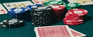 Zwei Karten liegen verdeckt auf dem Tisch. Davor befinden sich Casinochips sowie ein Turn.