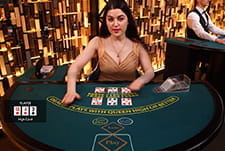 Die Poker Variante 3 Card Poker im Live Casino von Roxy Palace. Ein weiblicher Dealer im Spiel beim Geben der Karten.