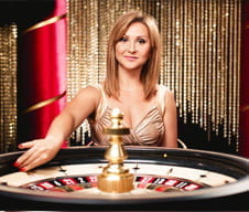 Auf dem Bild ist eine sunnyplayer Live Dealer zu sehen, die ein Roulettekessel dreht. Offenkundig hat sie Spaß.