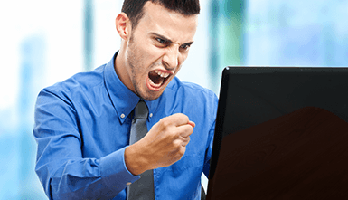 Ein Mann mit geballter Faust vor einem Laptop.