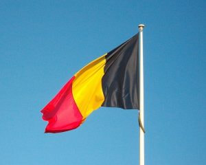 Die rot, gold, schwarze Fagge Belgiens im Wind bei blauem Himmel.