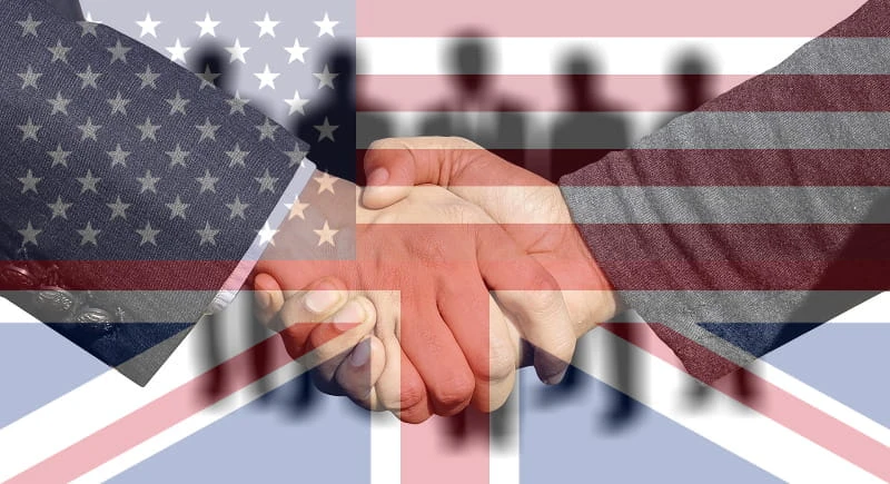 Foto eines geschäftlichen Handschlags hinter dem Schleier der britischen und der US-amerikanischen Flagge