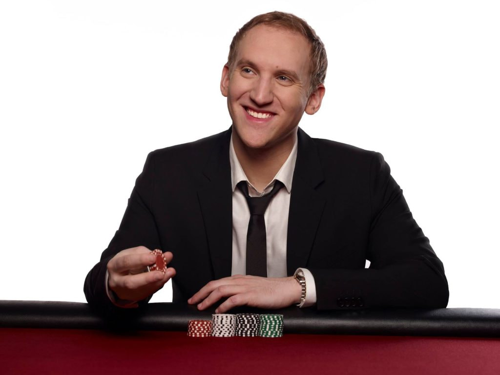 Jason Somerville im Anzug sitzend an einem Pokertisch.