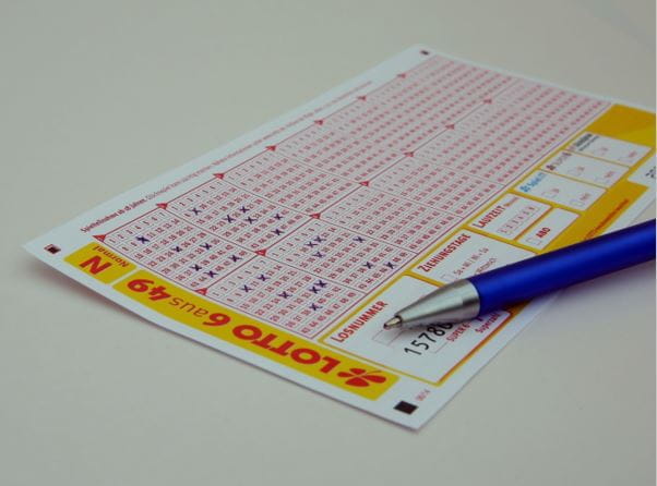 Ein ausgefüllter Lottoschein mit Stift auf einem Tisch.