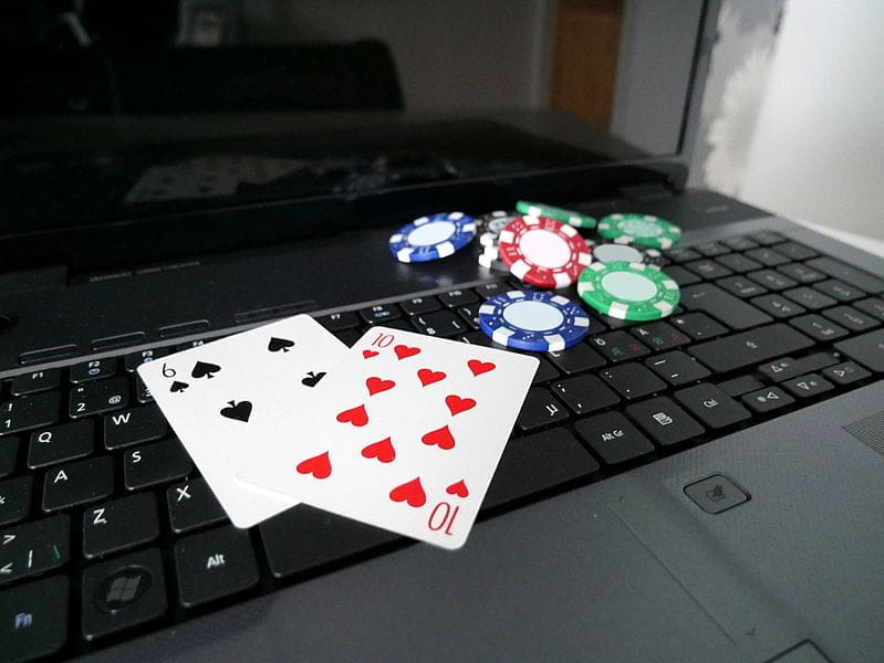 Ein Laptop mit zwei Spielkarten und mehreren Pokerchips.
