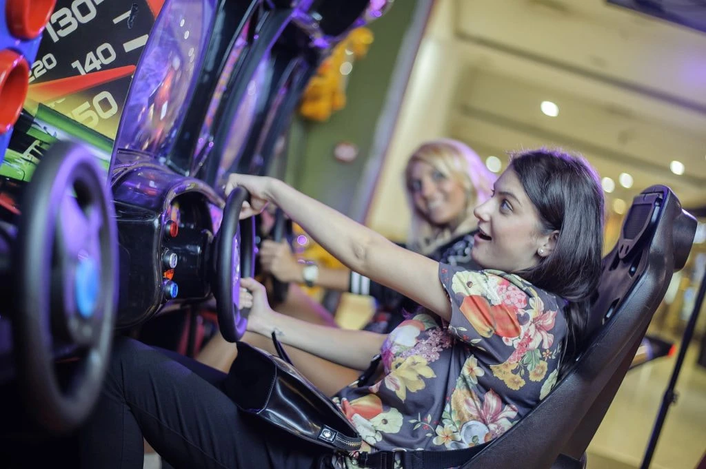 Zwei Frauen an Arcade-Spielautomaten für ein Rennspiel.