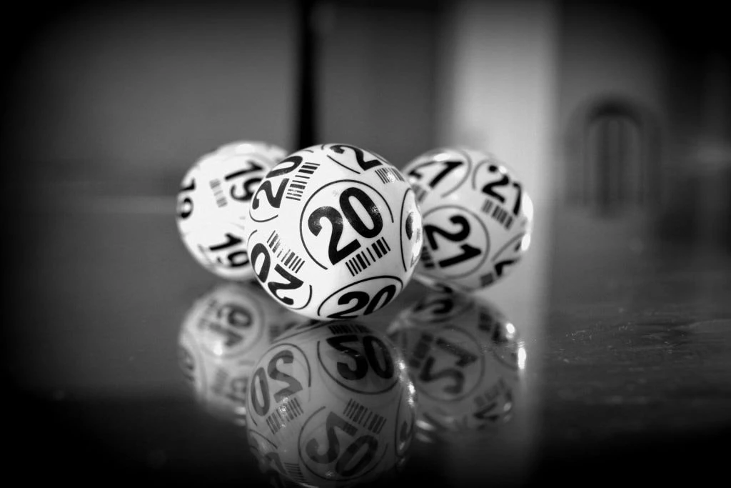 Drei Lotto-Kugeln mit den Zahlen 19, 20 und 21 auf einem Tisch.