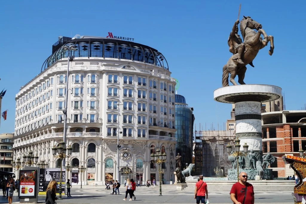 Der Hauptplatz mit einigen Menschen, der Statue von Alexander dem Großen auf einem Pferd und dem Marriott Hotel in Skopje.
