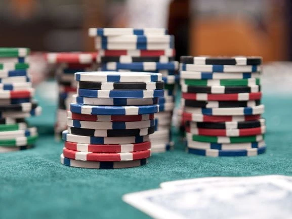 Verschiedene Pokerchips neben Spielkarten auf einem Tisch.