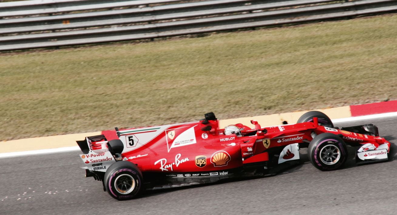 Ein roter Formel 1 Wagen von Ferrari in der Seitenansicht auf einer Rennstrecke. 
