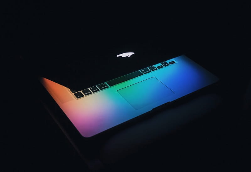 Ein Laptop leuchtet bunt in der Dunkelheit.