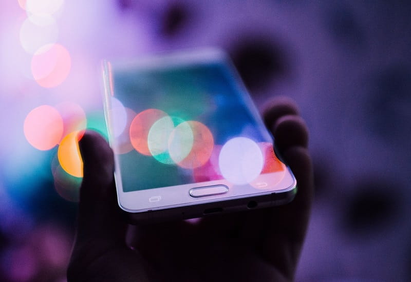 Ein Smartphone leuchtet in den Händen seines Nutzers.