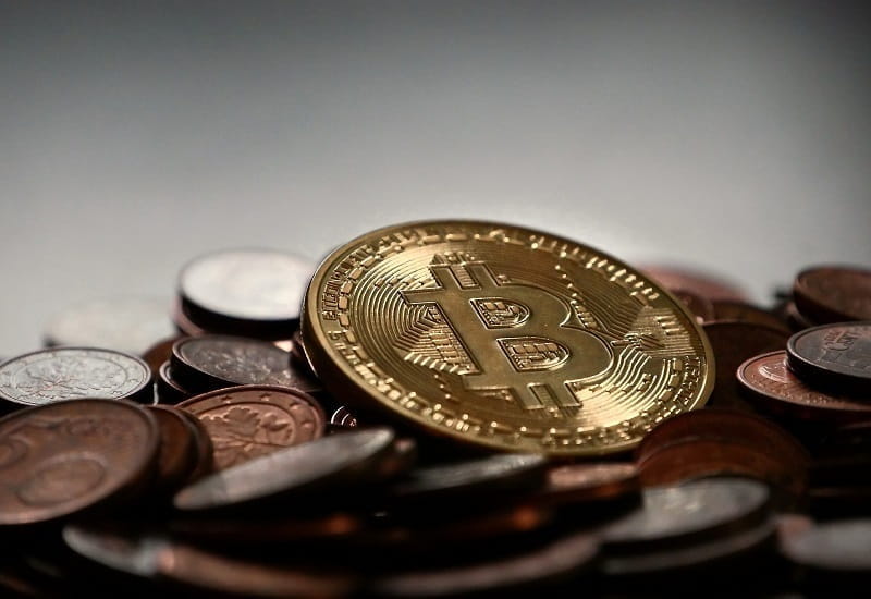 Eine Bitcoin-Münze auf einem Geldhaufen.