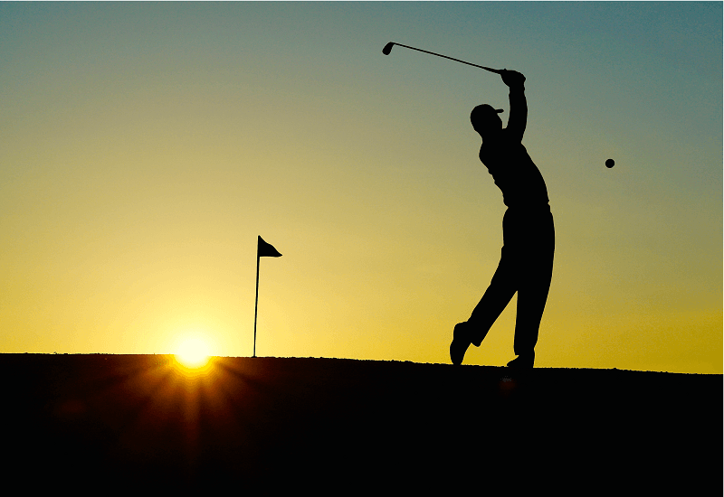 Die Silhouette eines Golfspielers beim Abschlag.