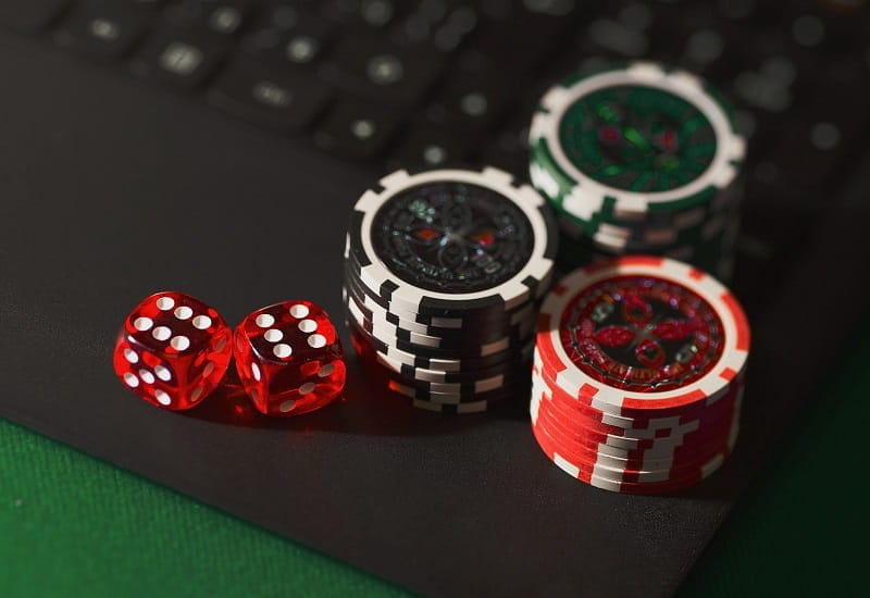 Pokerchips und Spielwürfel auf einem Laptop.