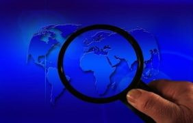 Eine Lupe untersucht eine Weltkarte.