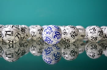 Weiße und blaue Lottobälle auf einer Tischfläche.