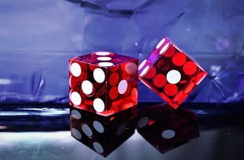 Zwei rote Casino-Spielwürfel auf einer Tischfläche.
