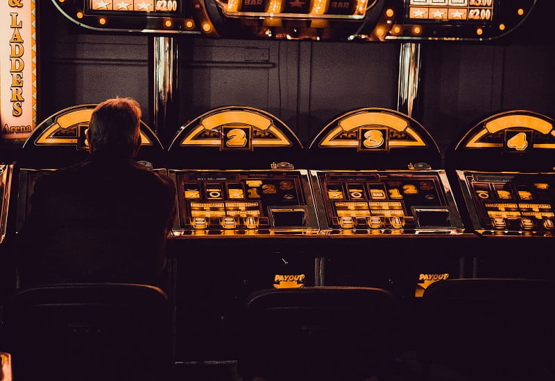 Ein Mann sitzt vor einem Spielautomaten.