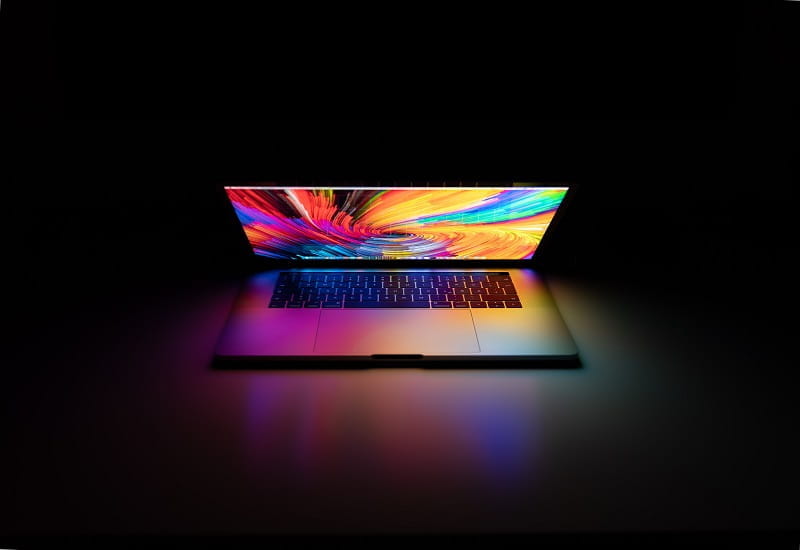 Der Bildschirm eines Laptops leuchtet in bunten Farben.