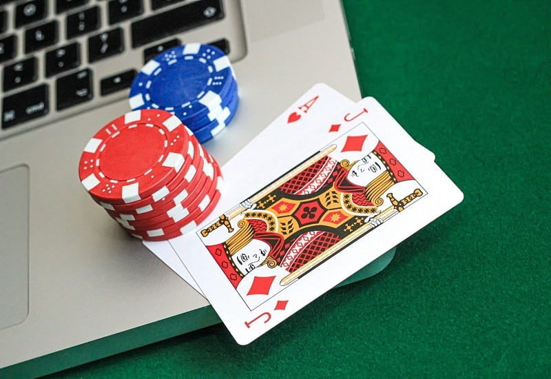 Pokerchips und Spielkarten auf einer Laptoptastatur.