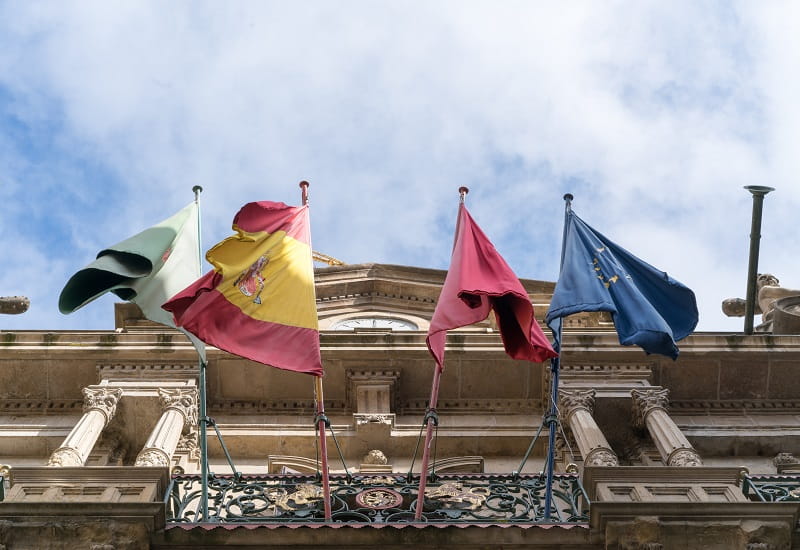 Spanische und europäische Flaggen an einem Gebäude. 