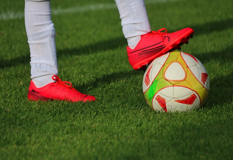 Ein Spieler mit orangenen Fußballschuhen am Ball.