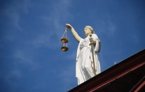 Eine Staue der Justitia auf einem Gebäude.