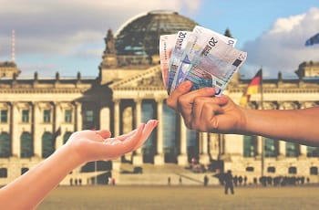 Geldscheine werden vor dem Berliner Bundestag überreicht.