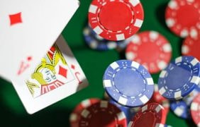 Spielkarten und Pokerchips fallen auf einen Spieltisch.