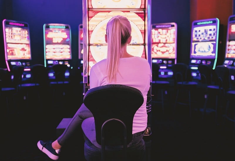 Eine Frau sitzt vor den Spielautomaten eines Casinos.