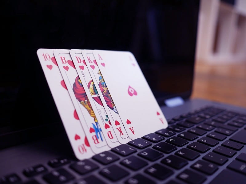 Spielkarten stehen aufgereiht auf einem Laptop.