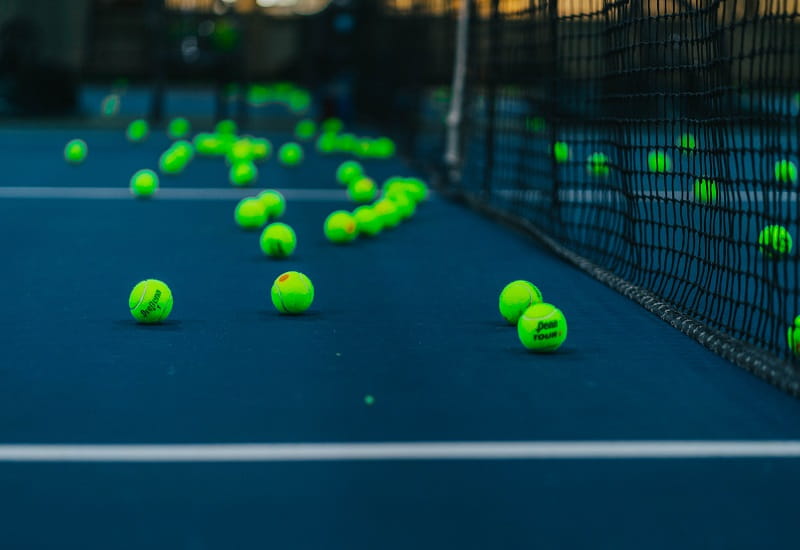 Tennisbälle liegen um das Mittelnetz verteilt.