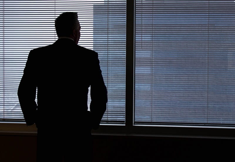 Die Silhouette eines Geschäftsmannes am Bürofenster.