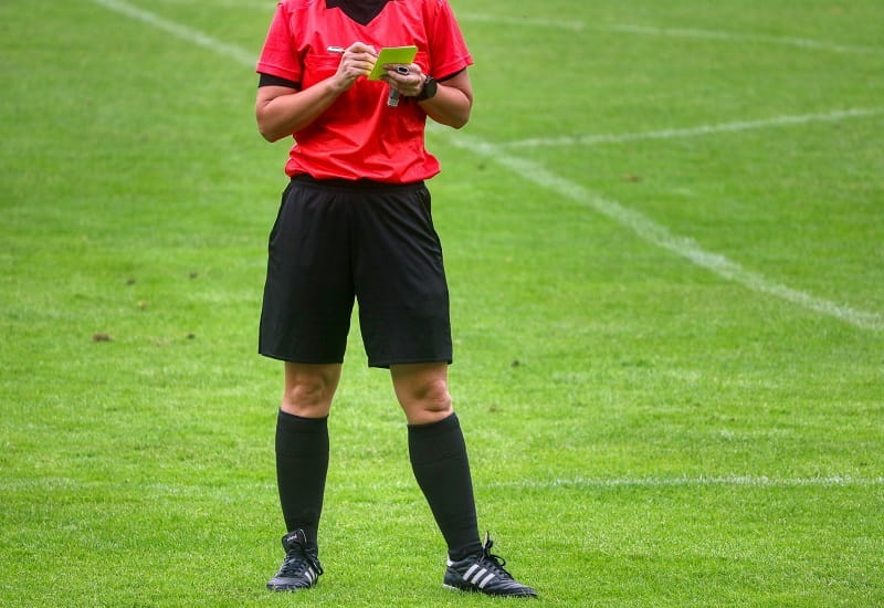 Ein Fußballschiedsrichter mit einer gelben Karte macht sich Notizen.