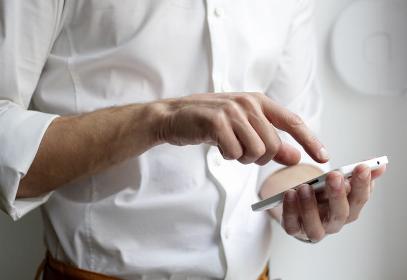 Ein Mann berührt das Display seine Smartphones.