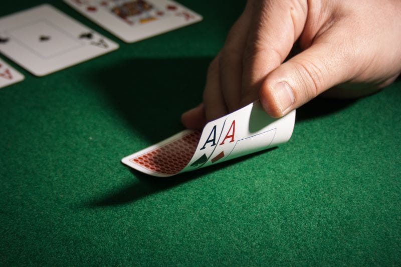 Person deckt beim Pokern zwei Asse auf.