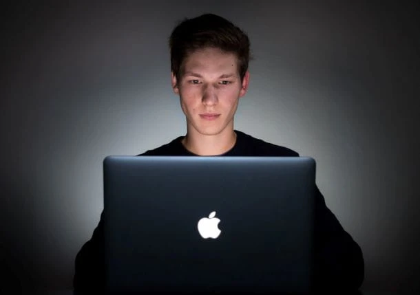 Jugendlicher sitzt bei Nacht vor dem Laptop.