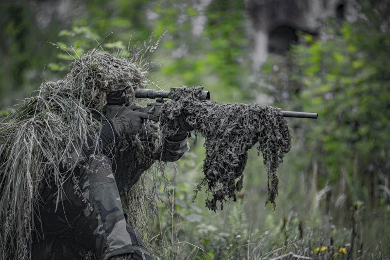 Sniper gut getarnt im Wald wie in einem Battle Royal.